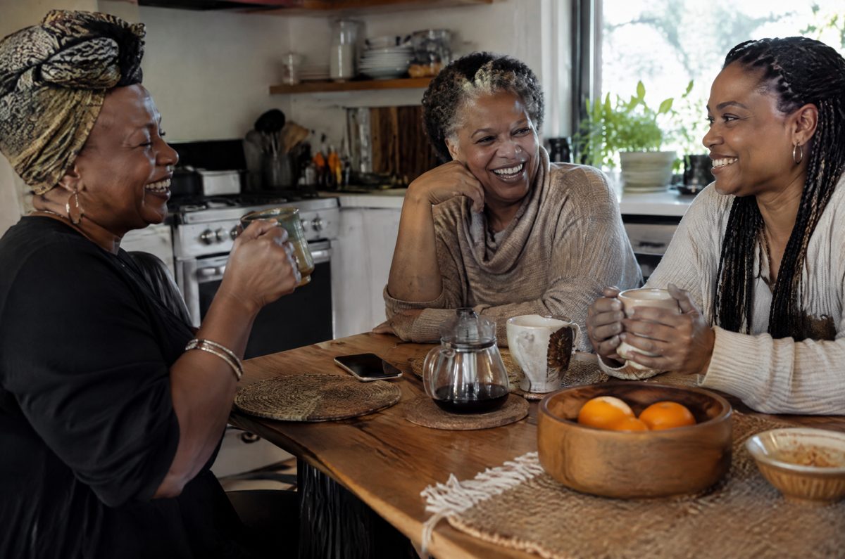 Three women laughing around a kitchen table